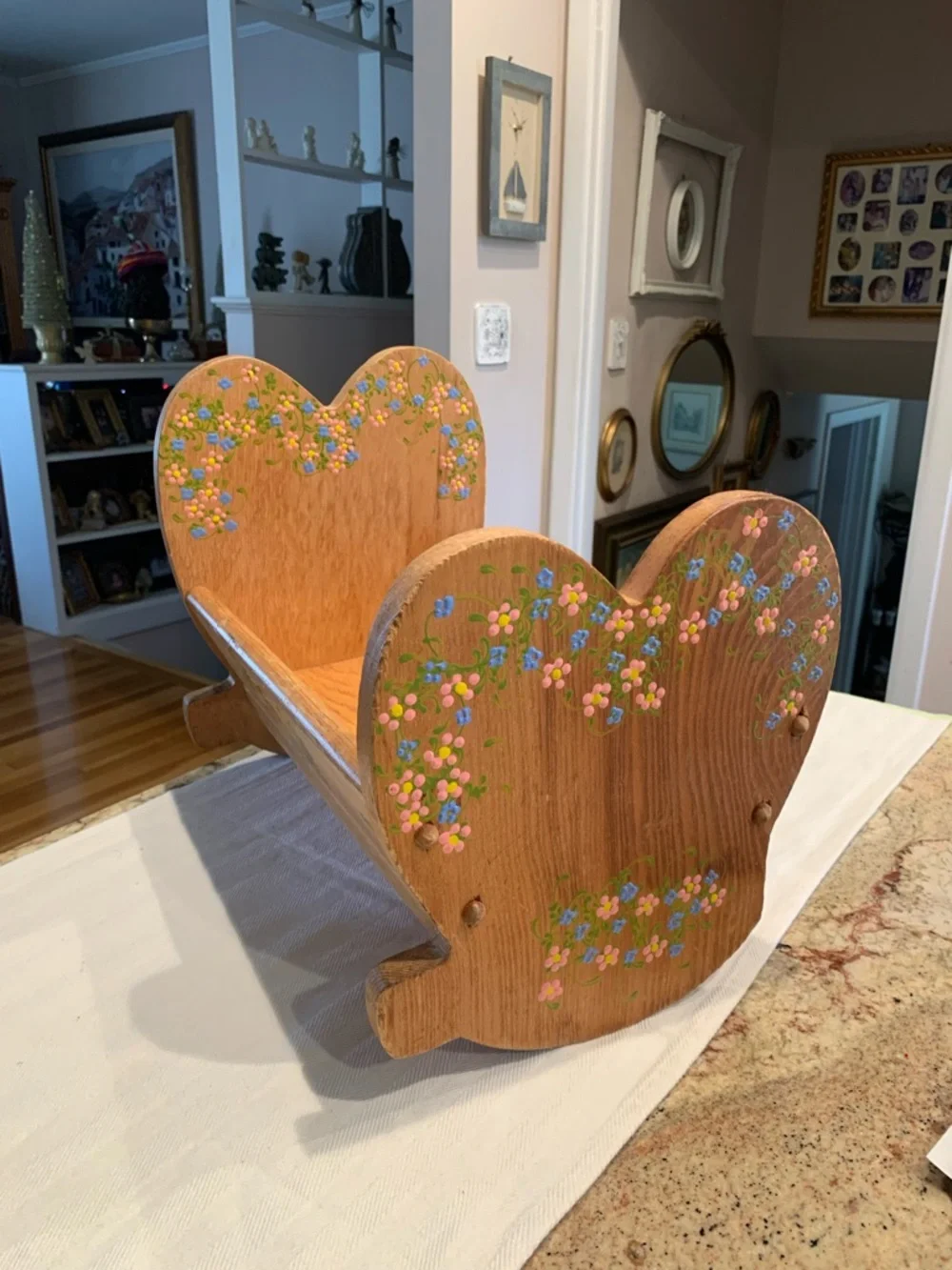 Vintage wooden doll cradle heart-shaped design painted with floral details.